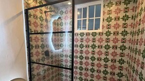 Un baño con cabina de ducha, inodoro y paredes con diseño.