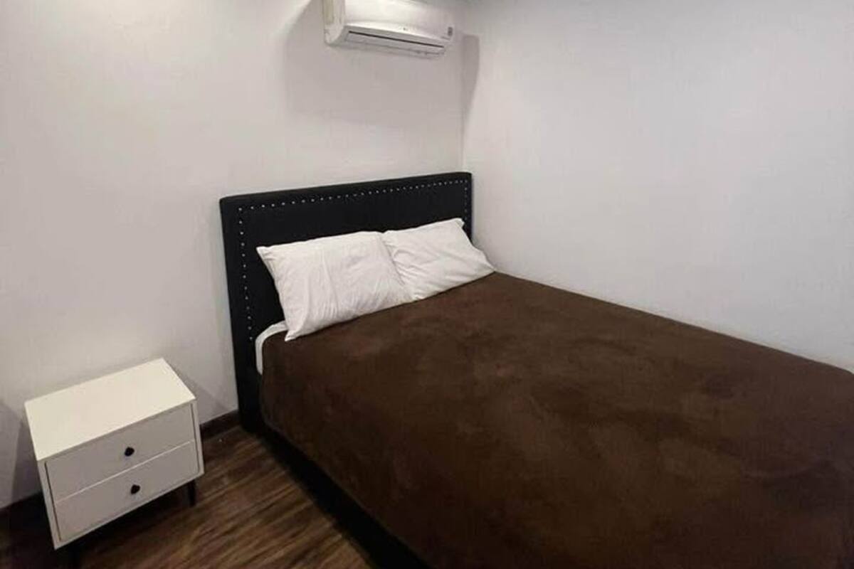 Une chambre avec un lit simple, une table de chevet et un appareil de climatisation.