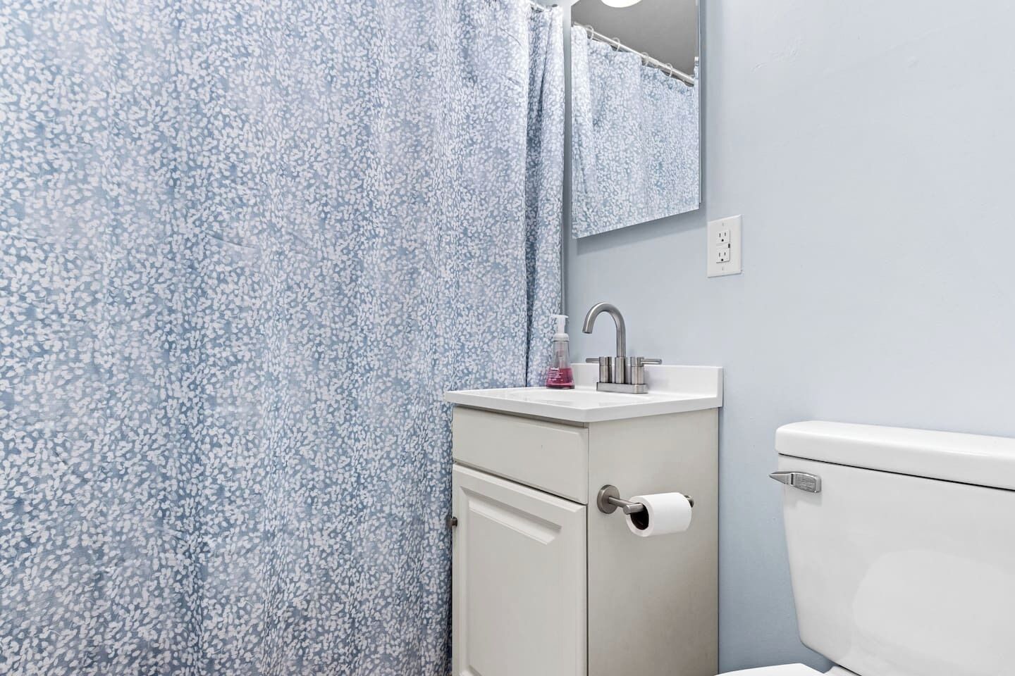 Ein Badezimmer mit Toilette, Waschbecken mit Spiegel und Duschvorhang.