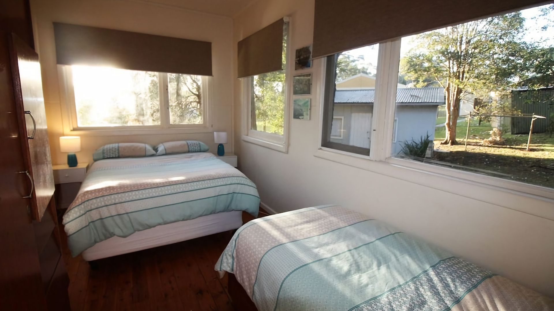 A bedroom with two beds, a window, and a view of the outside.