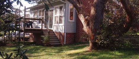 A two-story house with a front porch, a staircase leading to the second floor, and a large tree in the front yard.