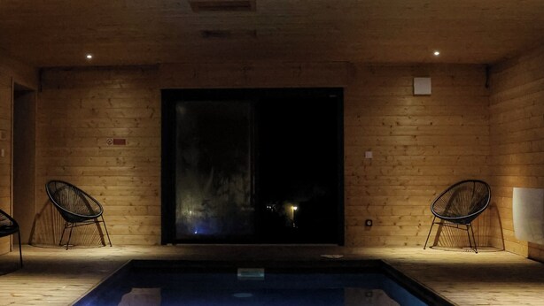 Un interno in legno con piscina, due sedie e un'ampia finestra.