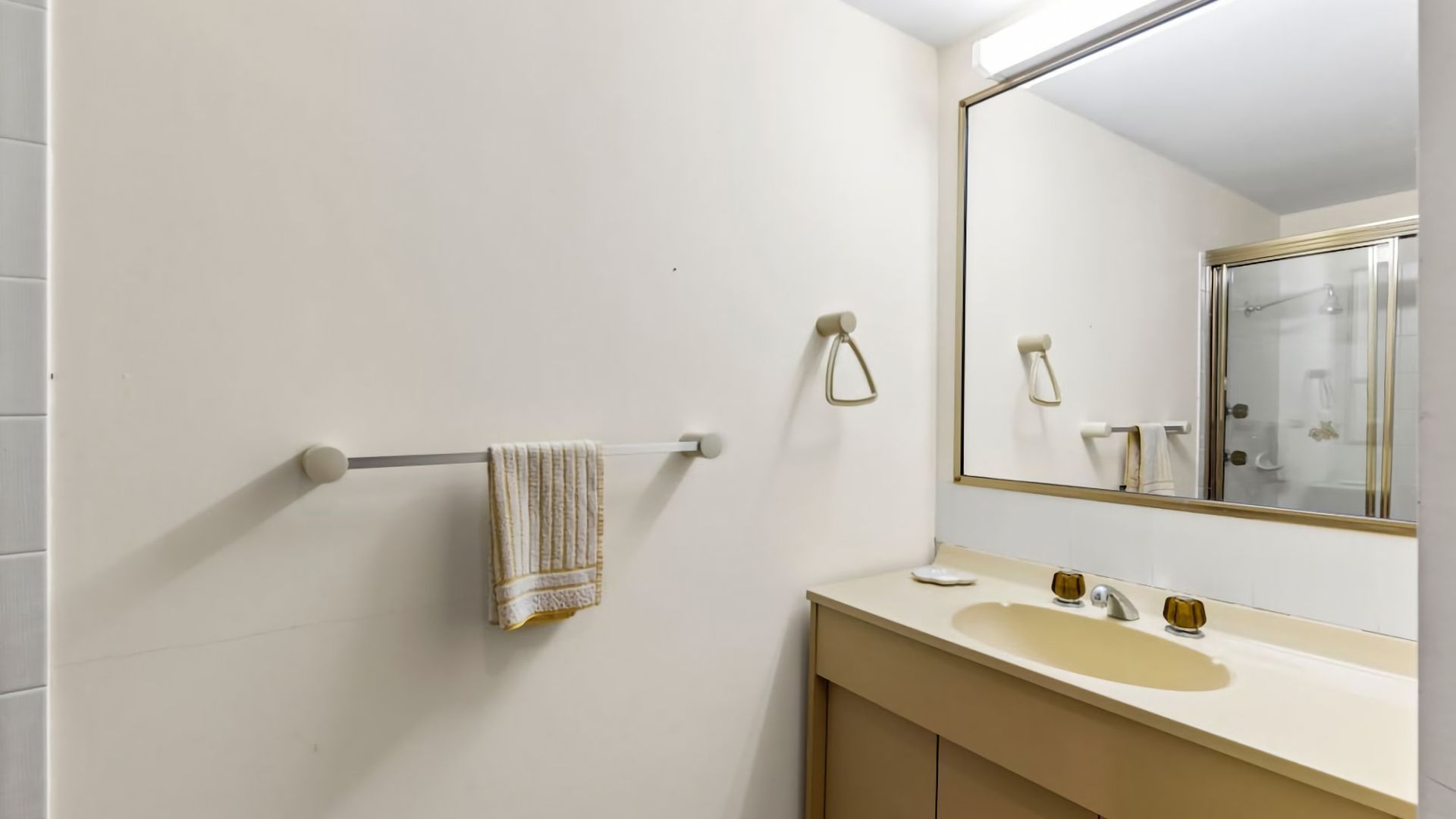 A bathroom with a white sink, a mirror, and a towel hanging on a towel rack.
