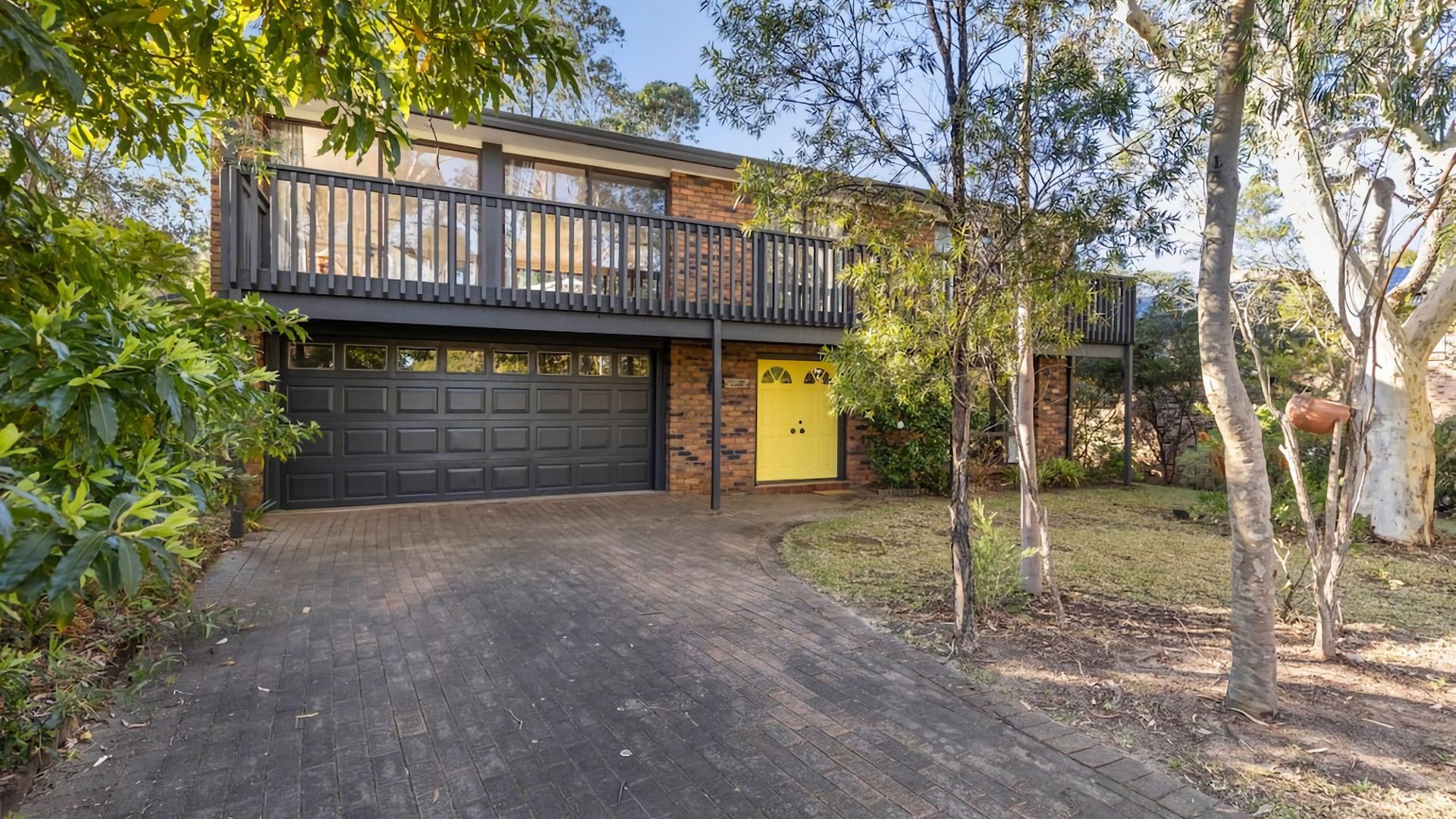 Une maison à deux étages avec un garage, un balcon et une pelouse bien entretenue.