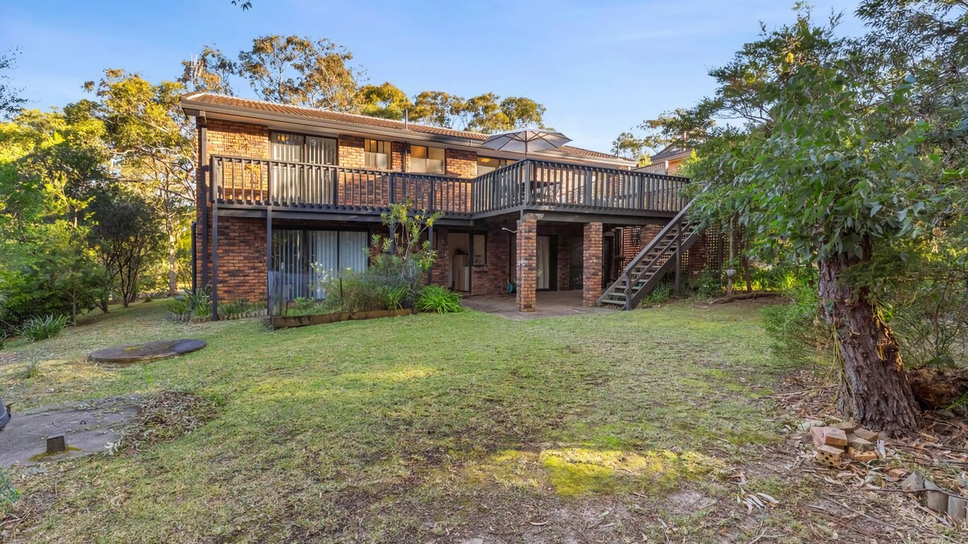 A two-story house with a balcony, a staircase, and a well-maintained garden.