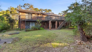 A two-story house with a balcony, a staircase, and a well-maintained garden. - Halliwag Haven is perfect for a family getaway (Cunjurong Point)