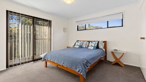 A bedroom with a large bed, a window, and a sliding glass door leading to an outdoor area. - Halliwag Haven is perfect for a family getaway (Cunjurong Point)