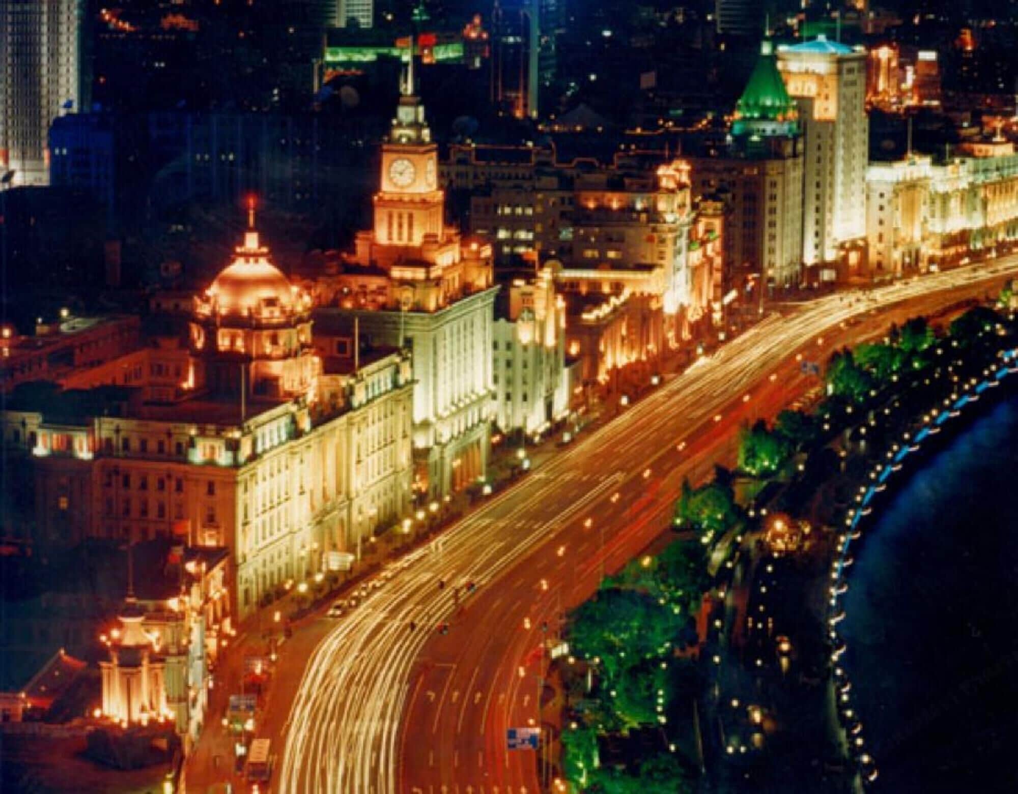 A nighttime cityscape with illuminated buildings and a multi-lane highway.