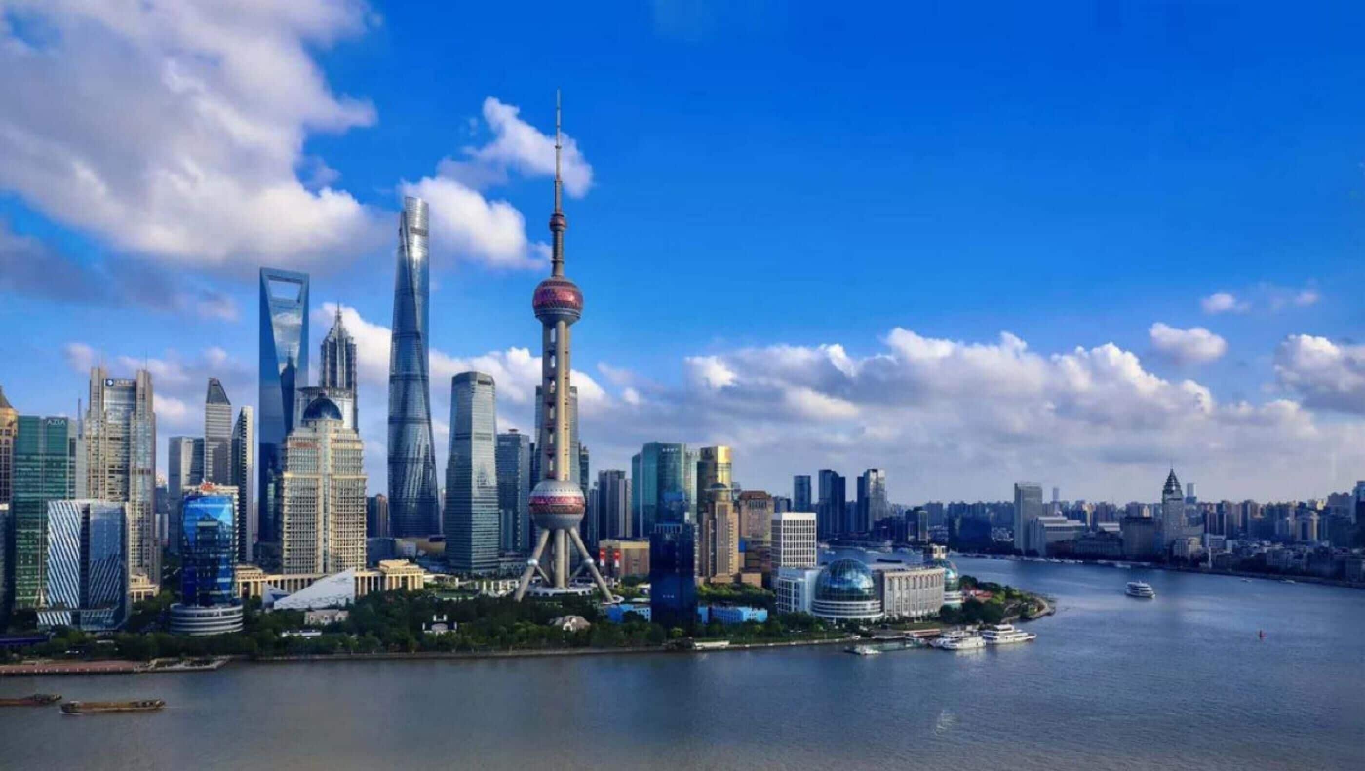 A city skyline with modern skyscrapers, a prominent tower, and a body of water in the foreground.