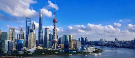 A city skyline with modern skyscrapers, a prominent tower, and a body of water in the foreground.