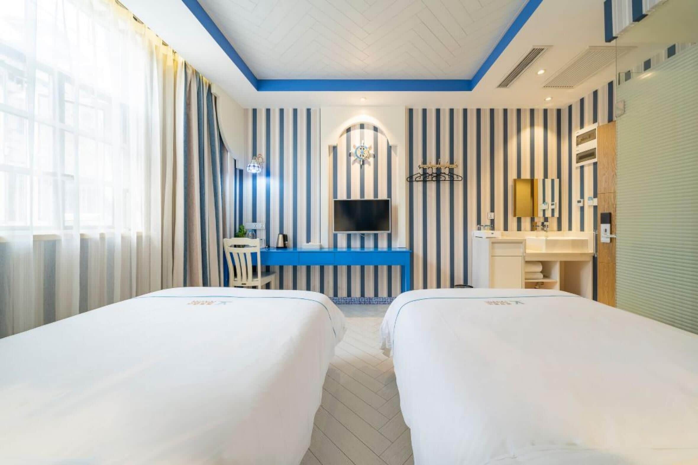 A hotel room with two beds, a TV, a desk, and a bathroom.