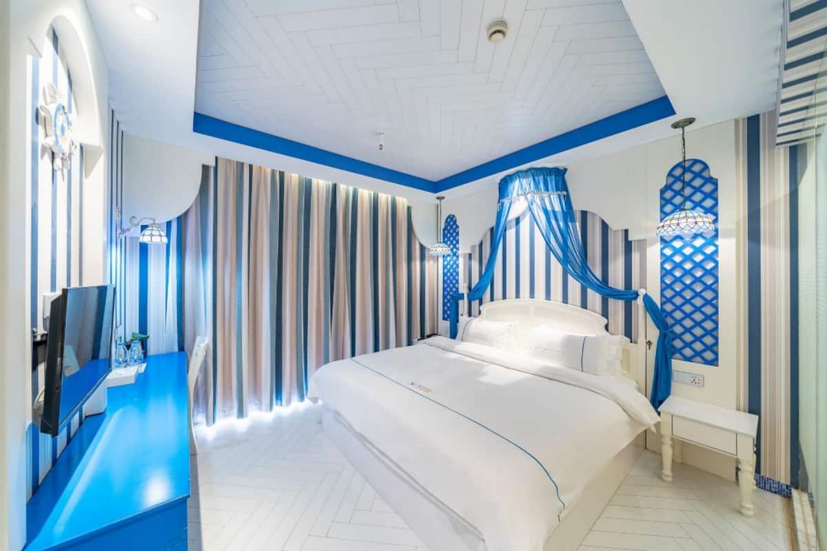 Ein Schlafzimmer mit einem Bett, einem Fernseher und Vorhängen.