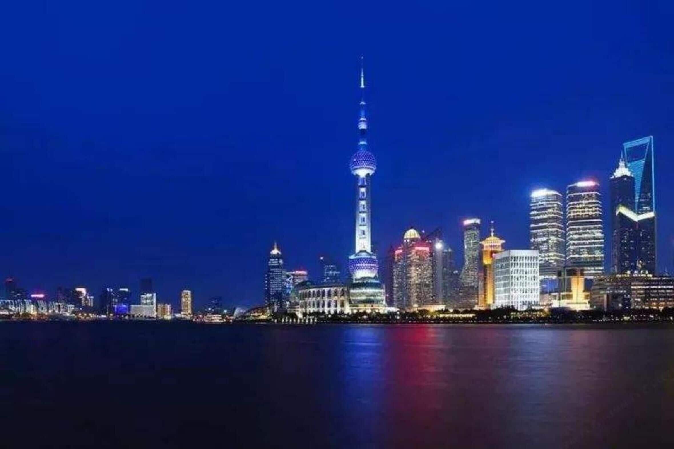 Un horizonte urbano nocturno con una torre destacada y edificios modernos.