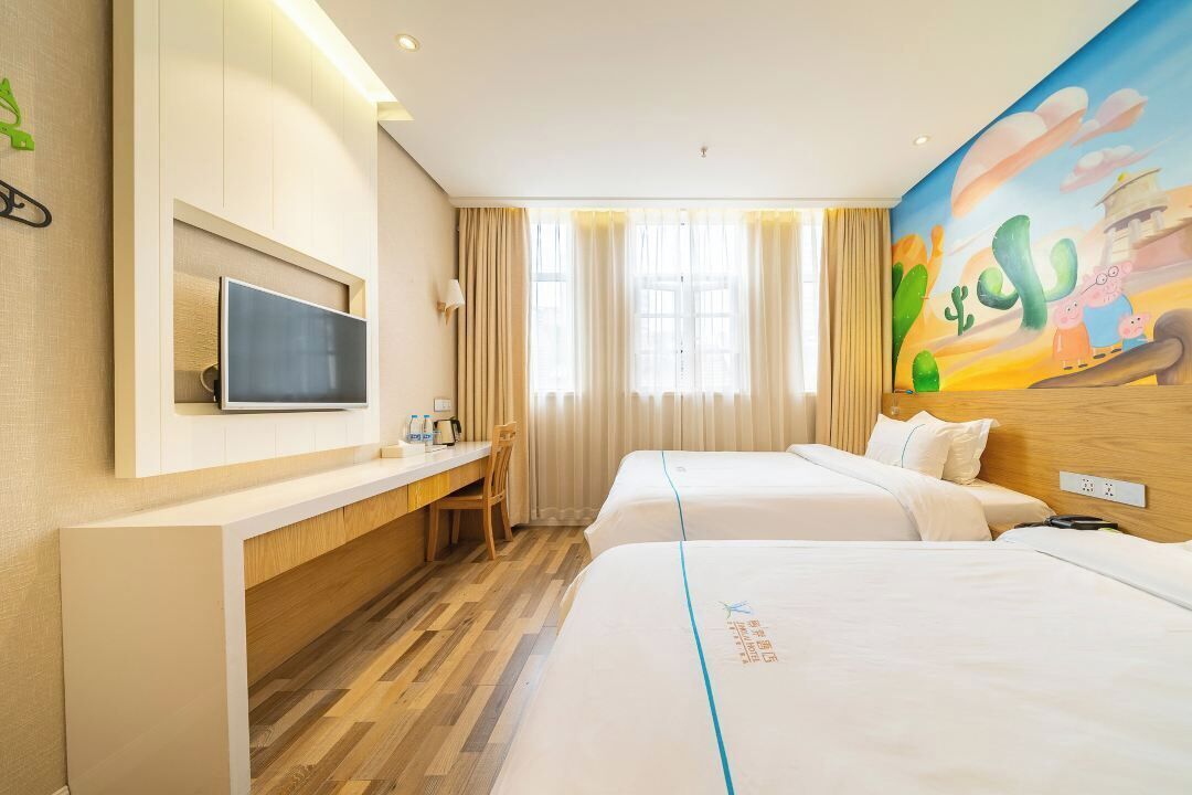 A hotel room with two beds, a desk, a TV, and a mural on the wall.