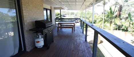 An outdoor patio with a barbecue grill, a gas tank, and a hammock.