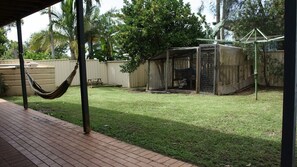 A backyard with a hammock, a fenced play area, and a covered structure. - Holiday Haven is a spacious home (Manyana)