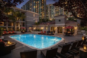 A pool area with lounge chairs and a dining table, surrounded by tall buildings. - Stay Demo 1BA Hideaway In Marina Del Rey (Marina del Rey)