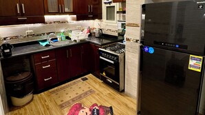 Una cocina moderna con armarios de madera oscura, un refrigerador de acero inoxidable y un horno empotrado.