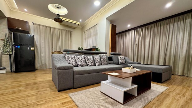 Una sala moderna con un sofá gris, una mesa de centro y un refrigerador negro.