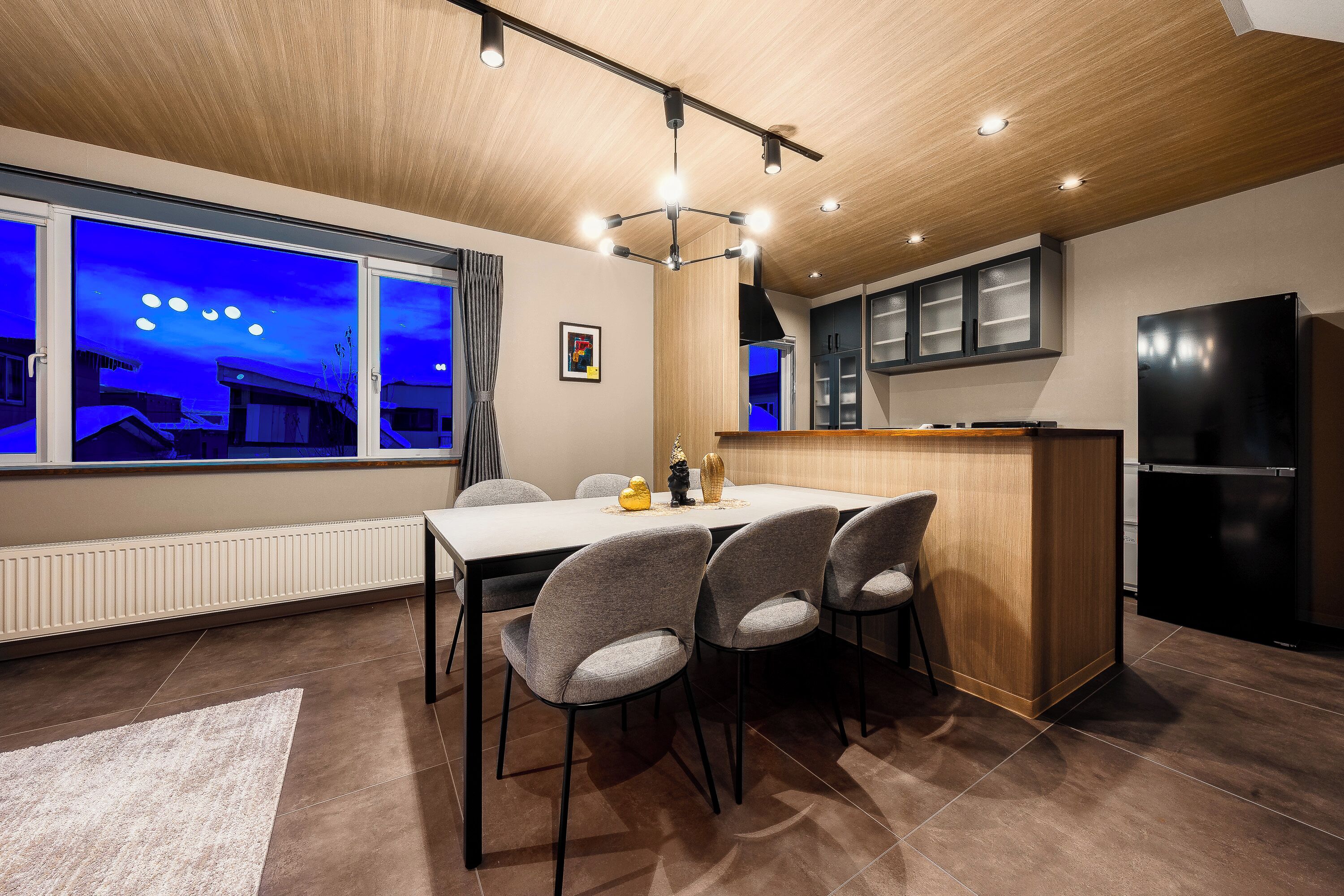 A modern kitchen with a black refrigerator, a wooden countertop, and a dining area with a table and chairs.