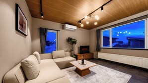 A modern living room with a sofa, a coffee table, and a TV. - ASTAGE VILLA KAMIFURANO (Kamifurano)