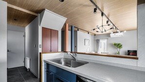 A modern kitchen with a built-in dishwasher, a stainless steel sink, and a wooden ceiling. - ASTAGE VILLA KAMIFURANO (Kamifurano)