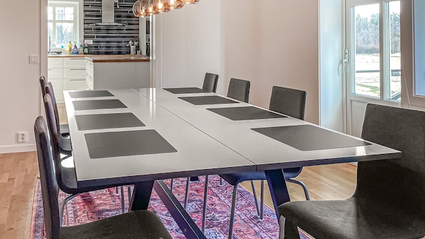 A modern dining area with a long table, chairs, and a kitchen in the background. - Gorgeous home in Ljungby with WiFi (Ljungby)