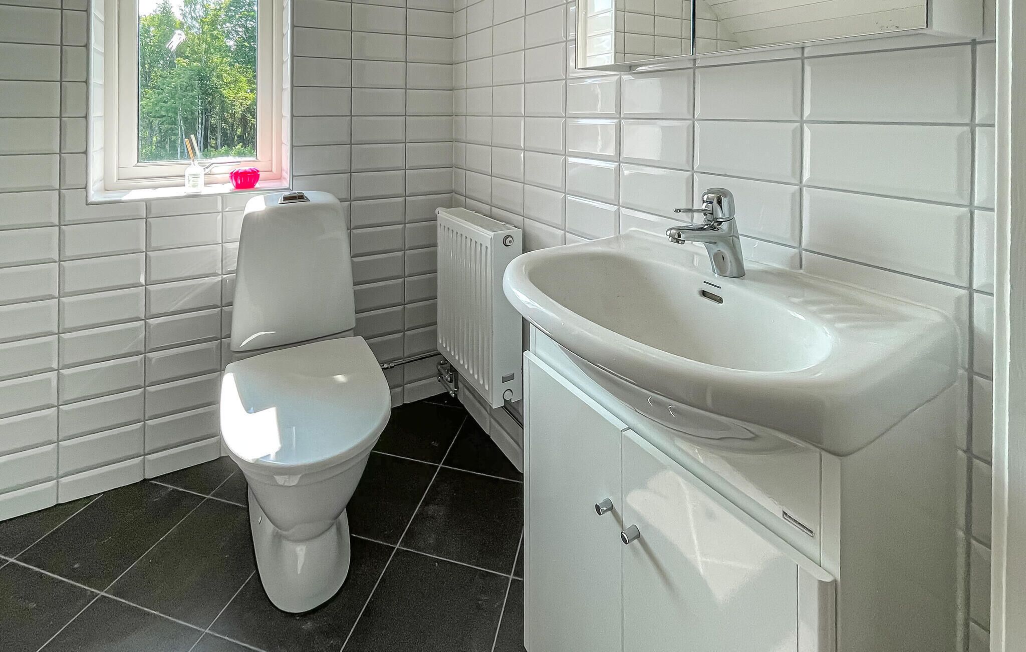 Un baño con inodoro, lavamanos y ventana.