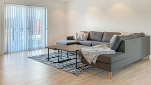 Een moderne woonkamer met een grijze bank, een salontafel en een tapijt met een patroon.