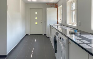 A modern kitchen with a built-in washer and dryer, a large window, and a door with small windows. - Gorgeous home in Ljungby with WiFi (Ljungby)