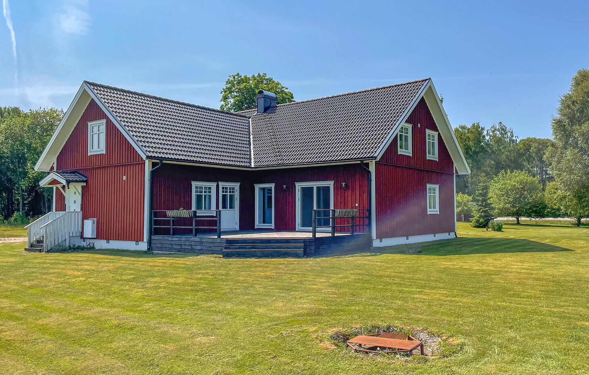 A red barn with a steep gabled roof, a porch with a bench, and a small staircase leading to the entrance.