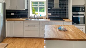 Een moderne keuken met witte kasten, een houten aanrecht en een groot raam voor natuurlijk licht.