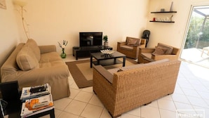 A living room with a sofa, two armchairs, a coffee table, a TV, and a bookshelf. - Villa in Vias With Private Pool & Garden (Vias)