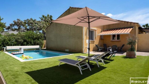 A backyard with a swimming pool, a covered patio area, and outdoor furniture. - Villa in Vias With Private Pool & Garden (Vias)
