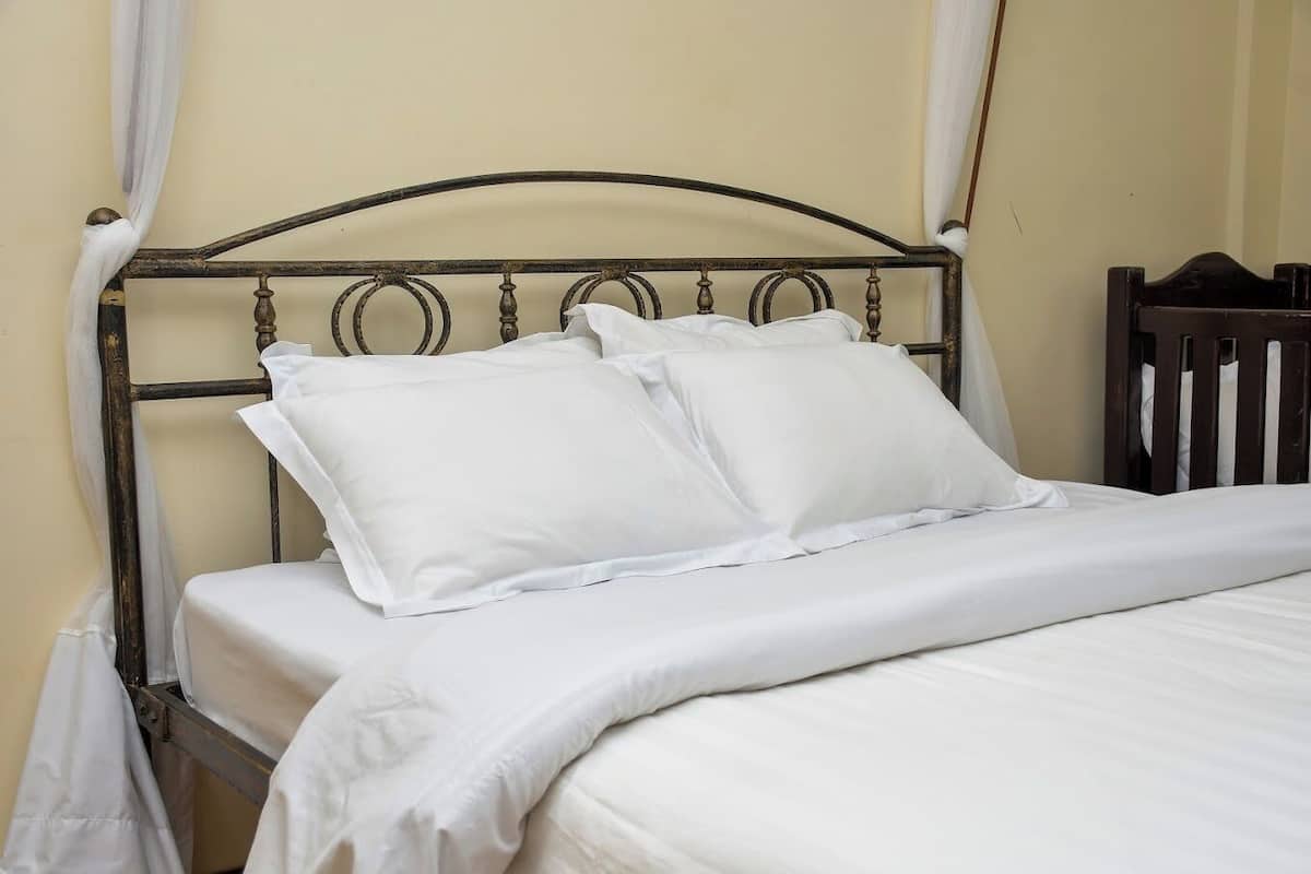 A bed with a metal headboard and white bedding.