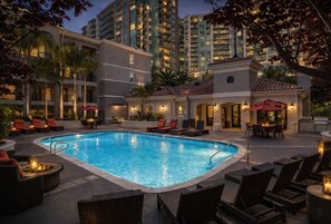 A swimming pool with lounge chairs and tables, surrounded by buildings with balconies and outdoor lighting. - Demolar 1 BR Stay In MDR (Marina del Rey)