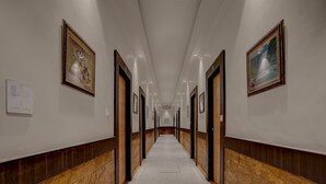 Un long couloir étroit aux murs et aux portes en marbre, qui mène à plusieurs pièces.