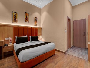A hotel room with a large bed, wooden headboard, and a nightstand with a lamp. There are three framed artworks on the wall above the bed. - Collection O Company Bagh Amritsar (Amritsar)
