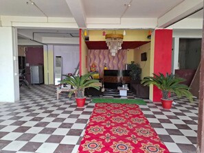 Een hotel lobby met een geruite vloer, een rode loper en potplanten.