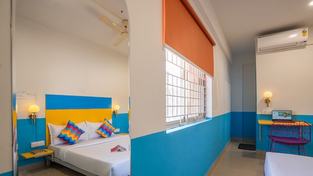 Habitación de hotel con cama, mesita de noche, lámpara y escritorio con silla.
