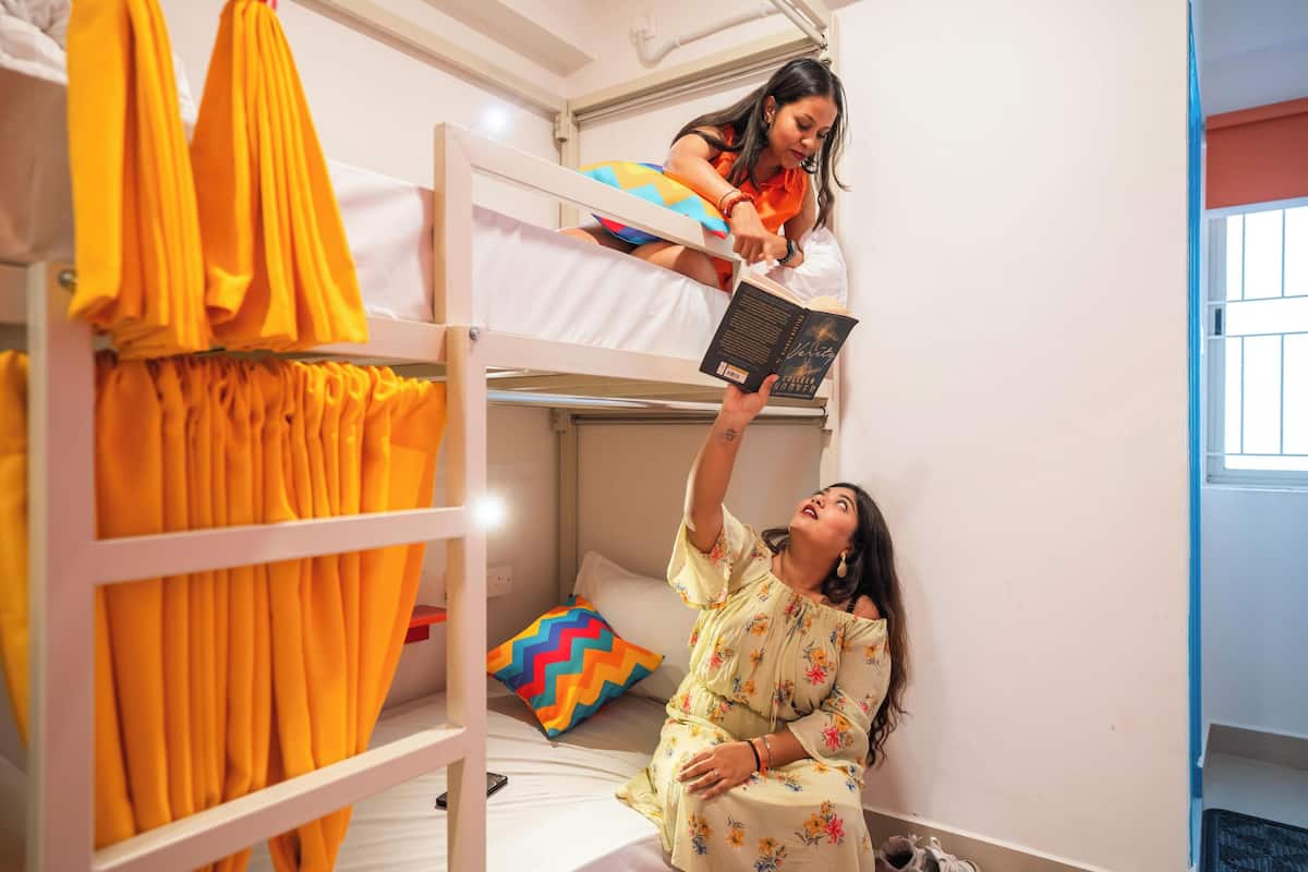 A bunk bed room with a person reading a book.