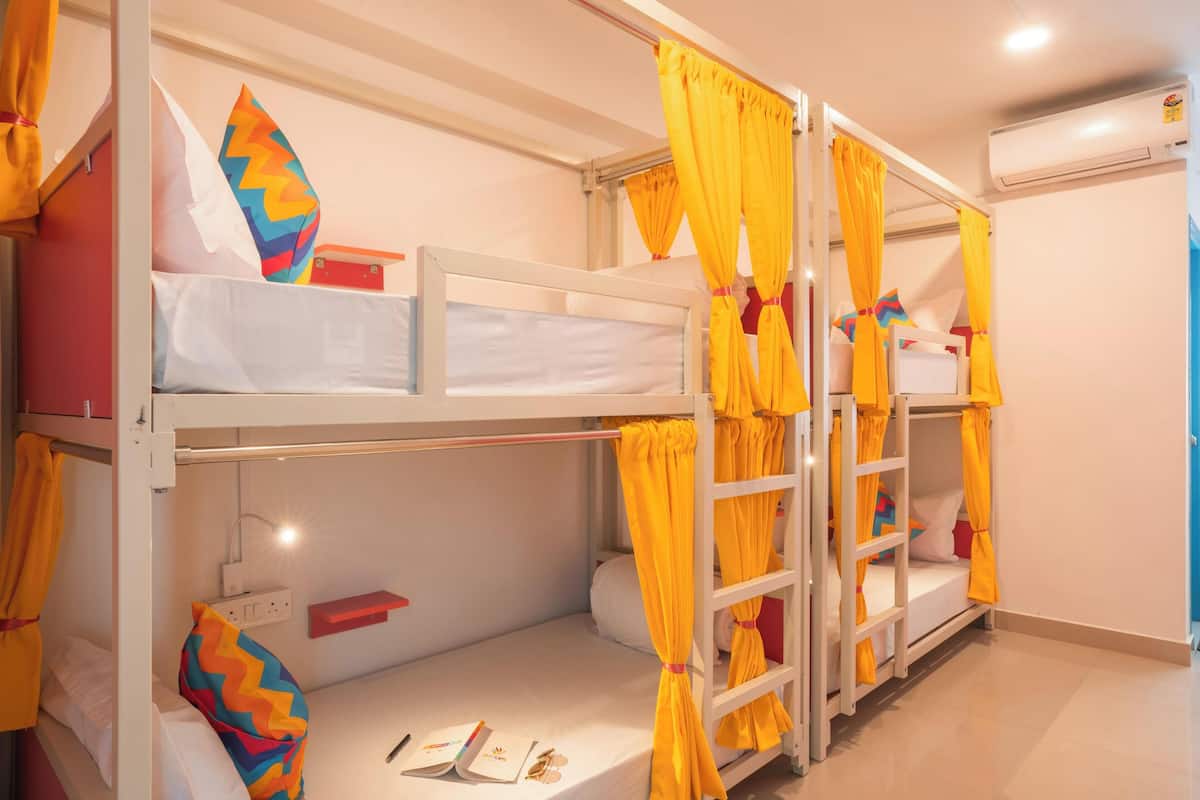 A bunk bed room with yellow curtains, a bedside table, and a reading light.