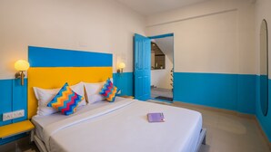 Una habitación de hotel con una cama, una mesita de noche y una puerta que da a otra habitación.