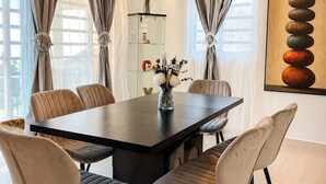 Une salle à manger moderne avec une table en bois foncé, des chaises recouvertes d’un tissu beige et un vase décoratif posé sur la table.