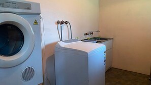 Ein Waschraum mit einer Frontlader-Waschmaschine, einem Trockner und einem Waschbecken.