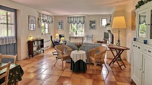 Ein gemütliches Wohnzimmer mit Kamin, einem Essbereich mit Tisch und Stühlen sowie einem Fernseher im Hintergrund.