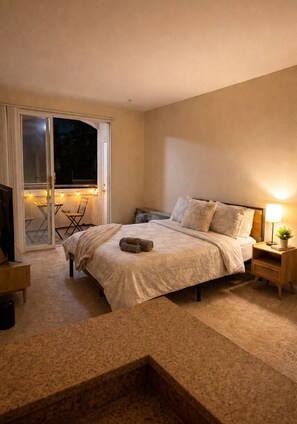 A bedroom with a bed, a nightstand, a lamp, and a sliding glass door leading to an outdoor area. - DS1 BR Getaway In MDR (Marina del Rey)
