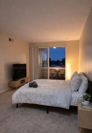 A bedroom with a bed, a TV, a desk, and a balcony with a table and chairs. - DS1 BR Getaway In MDR (Marina del Rey)