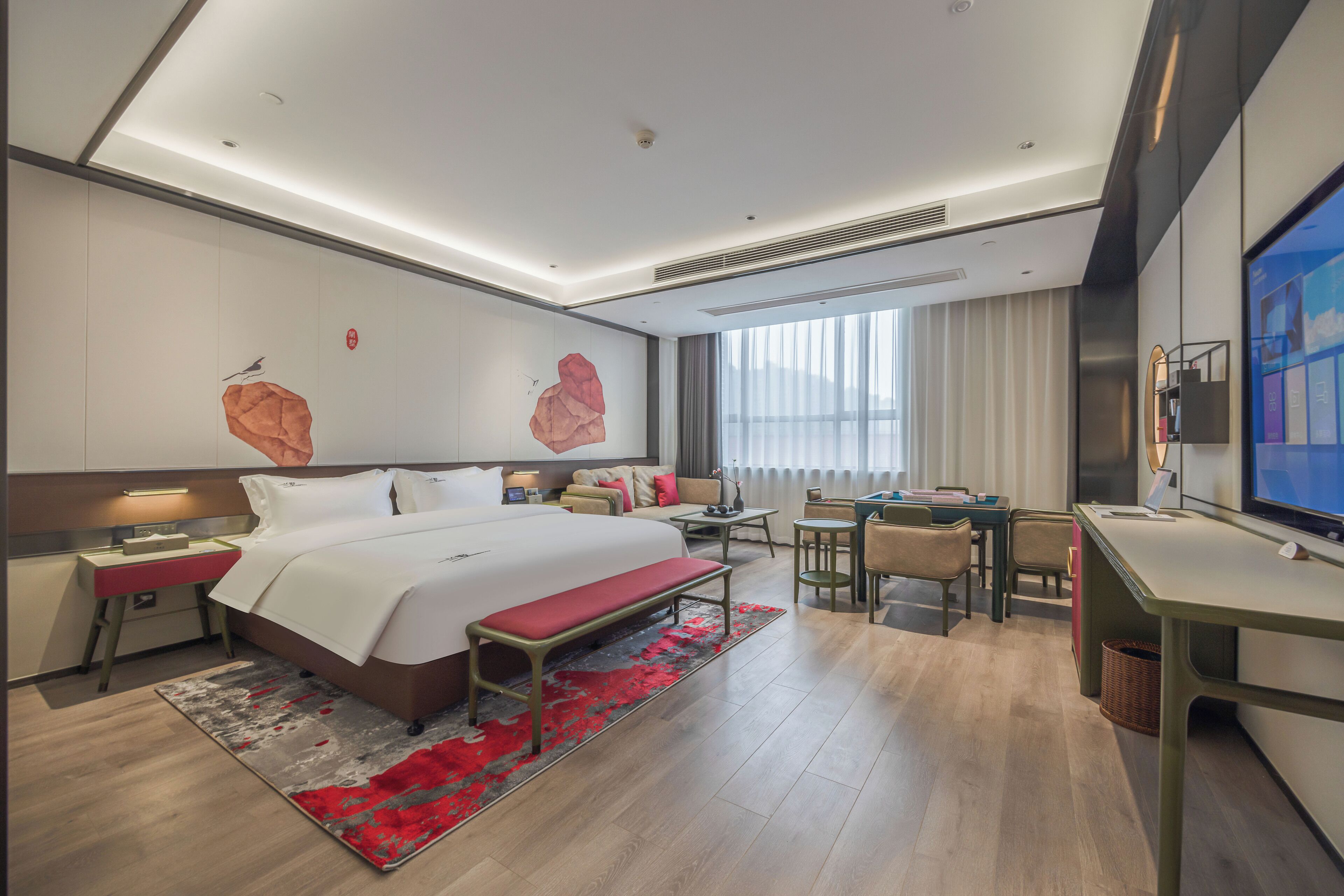 A modern hotel room with a large bed, a desk, a chair, a TV, and a window with curtains.