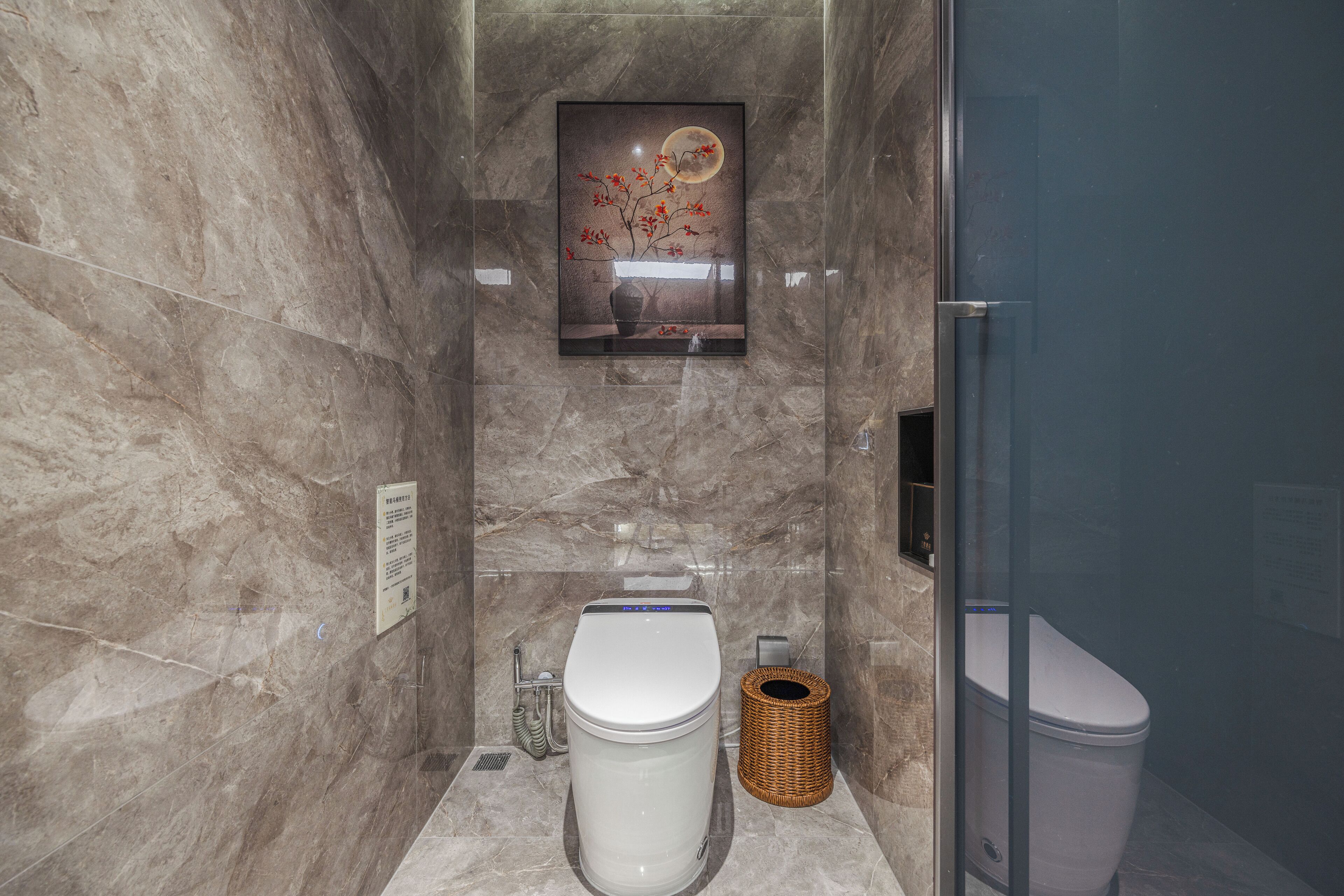 A modern bathroom with a toilet, bidet, and a framed artwork on the wall.